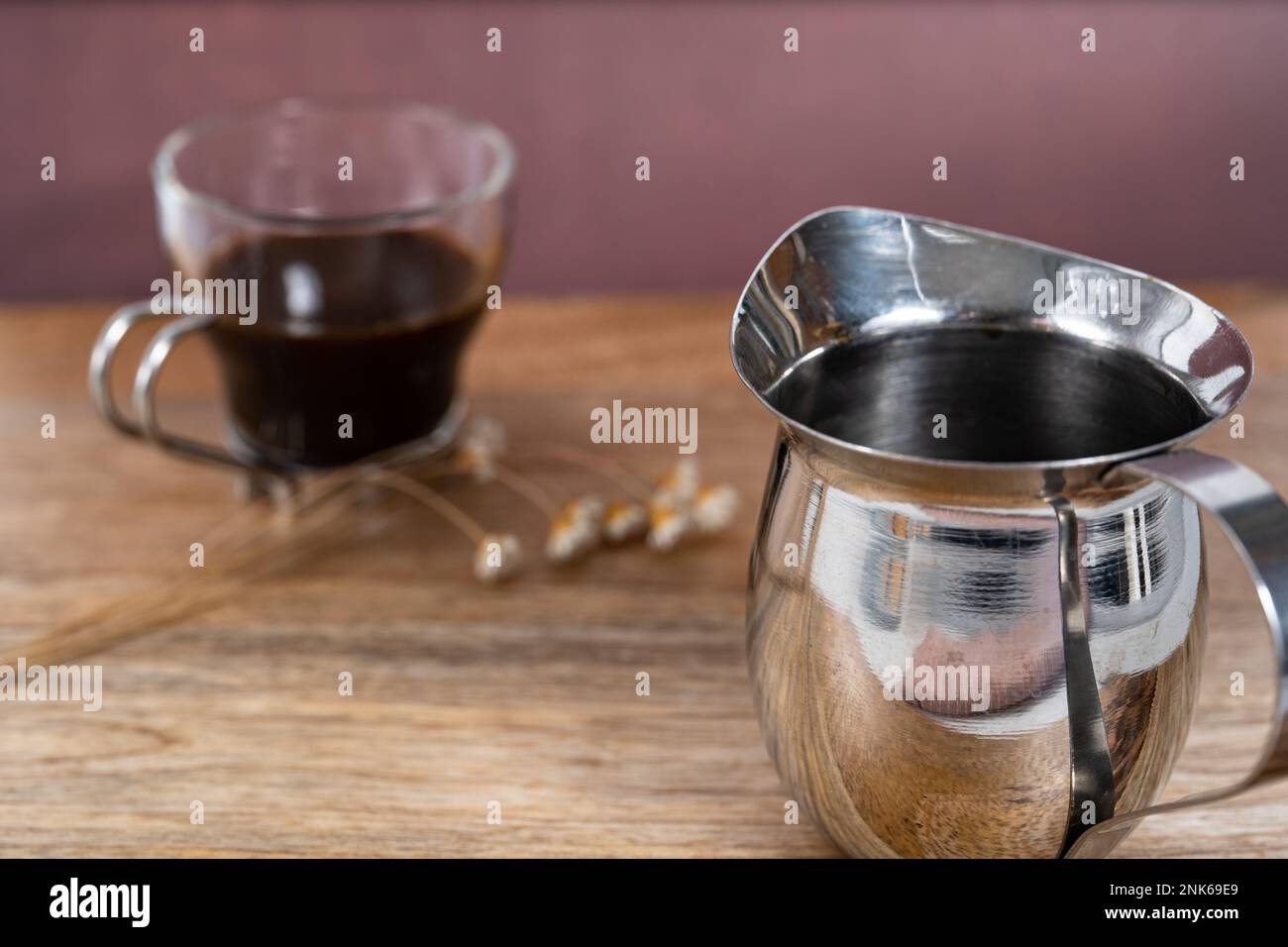 Espresso singolo in un bicchiere su un tavolo di legno con fiori secchi Foto Stock