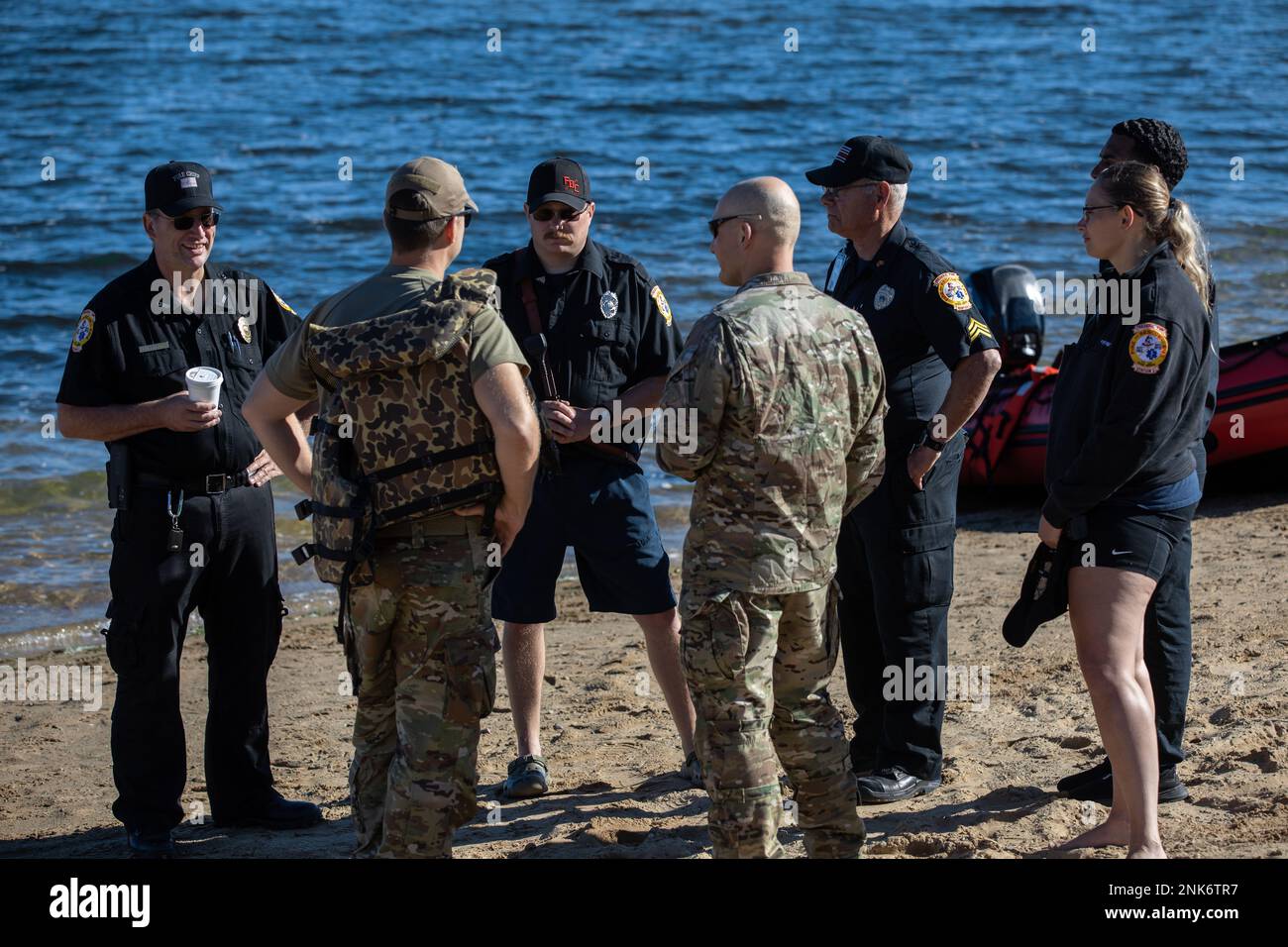 20th soldati del Gruppo delle forze speciali (Airborne) coordinano con i locali Roscommon, Michigan, vigili del fuoco e poliziotti sulle rive del lago Margrethe a Camp Grayling, Michigan, prima di un esercizio di helocast per i soldati che sostengono l'unità attraverso lo Sciopero settentrionale 22, 11 agosto 2022. Un Helocast è un metodo di inserimento utilizzato da forze operative speciali in cui un elicottero volerà sopra un corpo d'acqua per scendere da una barca e soldati che salteranno fuori, nuoteranno in barca e si sposteranno verso il loro bersaglio a terra. Foto Stock