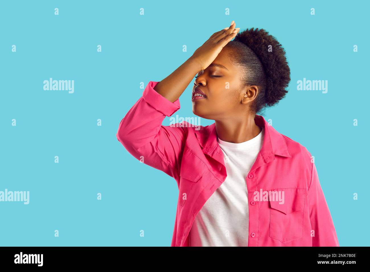 La giovane donna afroamericana sta mostrando un gesto facciale su sfondo blu. Foto Stock