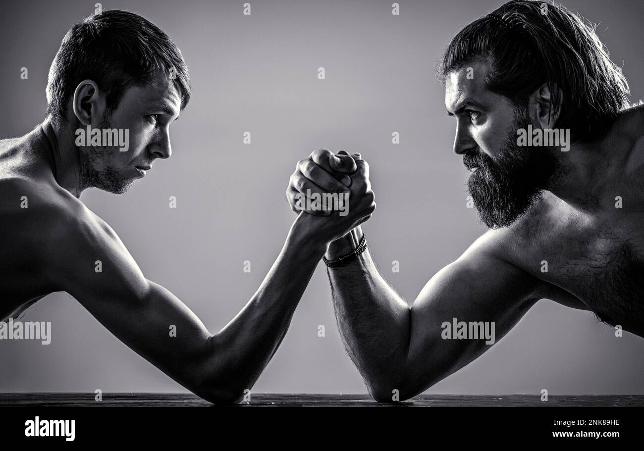 Braccia che lottano con una mano sottile, un braccio grande e forte in studio. Braccio uomo pesantemente muscoloso che lotta contro un uomo debole puny. Bianco e nero Foto Stock