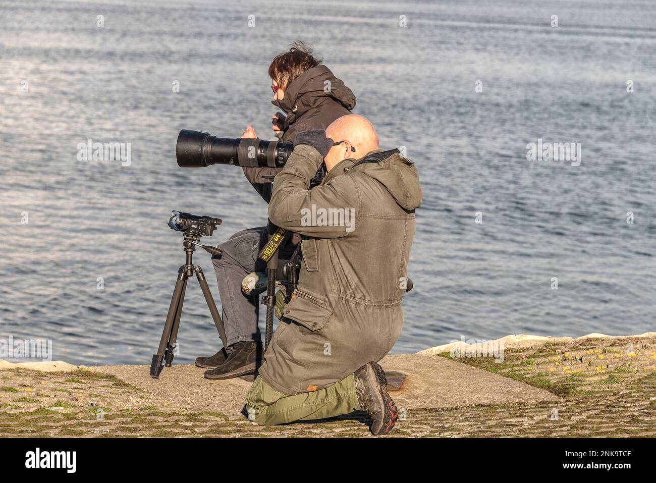 Il fotografo con un enorme teleobiettivo scatta foto sul canale del Mare del Nord a IJmuiden Velsen, Paesi Bassi Foto Stock