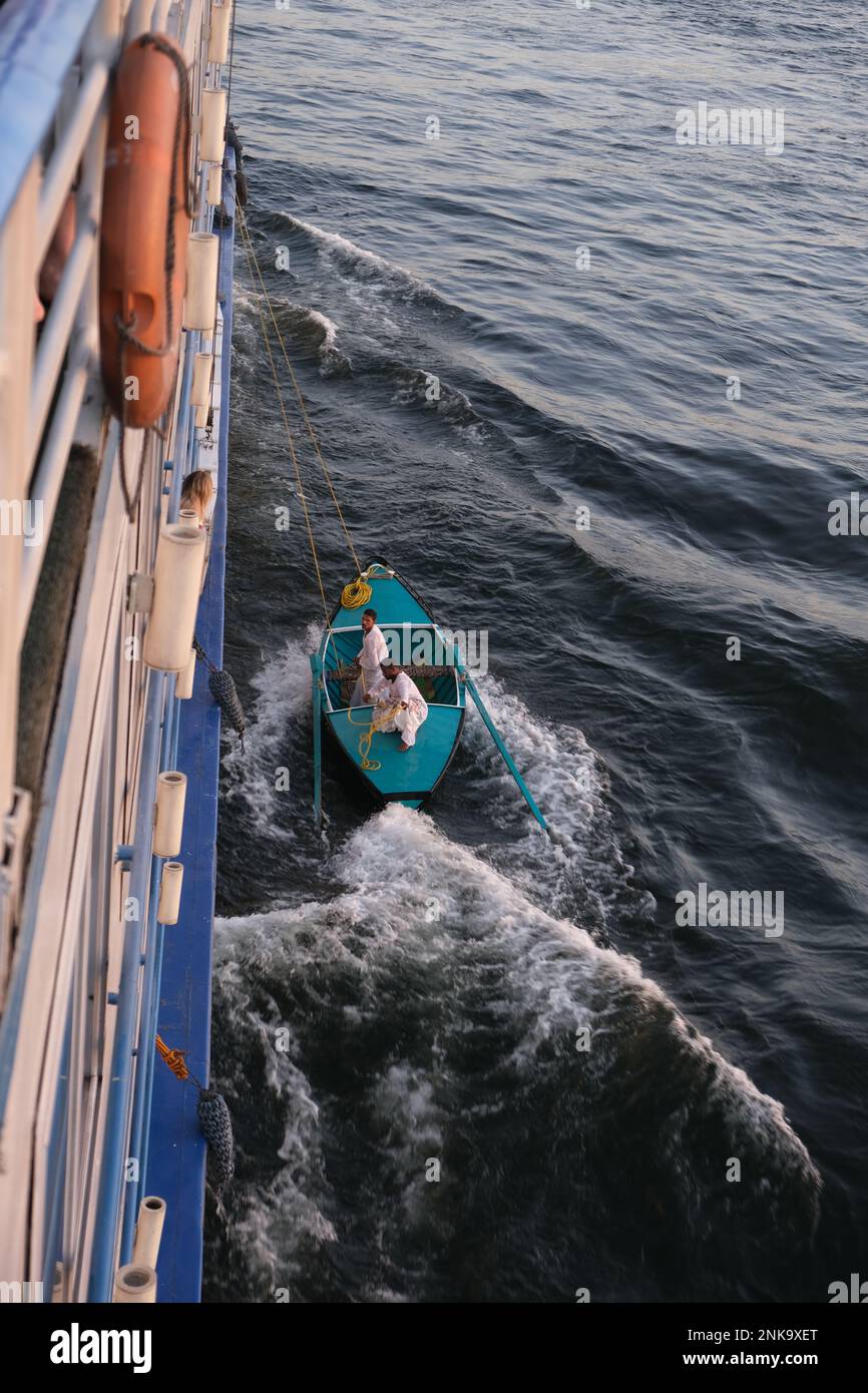 Uomini che vendono gioielli turistici e souvenir tessili da una piccola barca legata a una nave da crociera sul Nilo Foto Stock