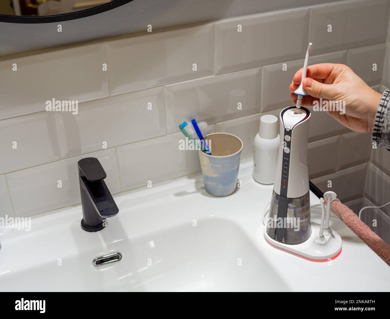 Le mani del giovane uomo che cambiano la sua punta domestica del flosser dell'acqua dentale Foto Stock