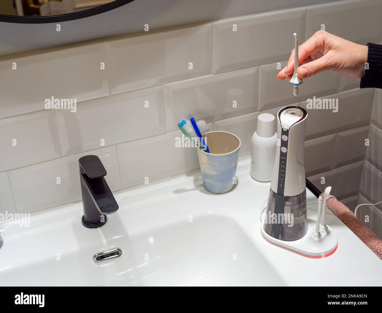 Le mani di giovane donna che cambiano la sua punta domestica del flosser dell'acqua dentale Foto Stock