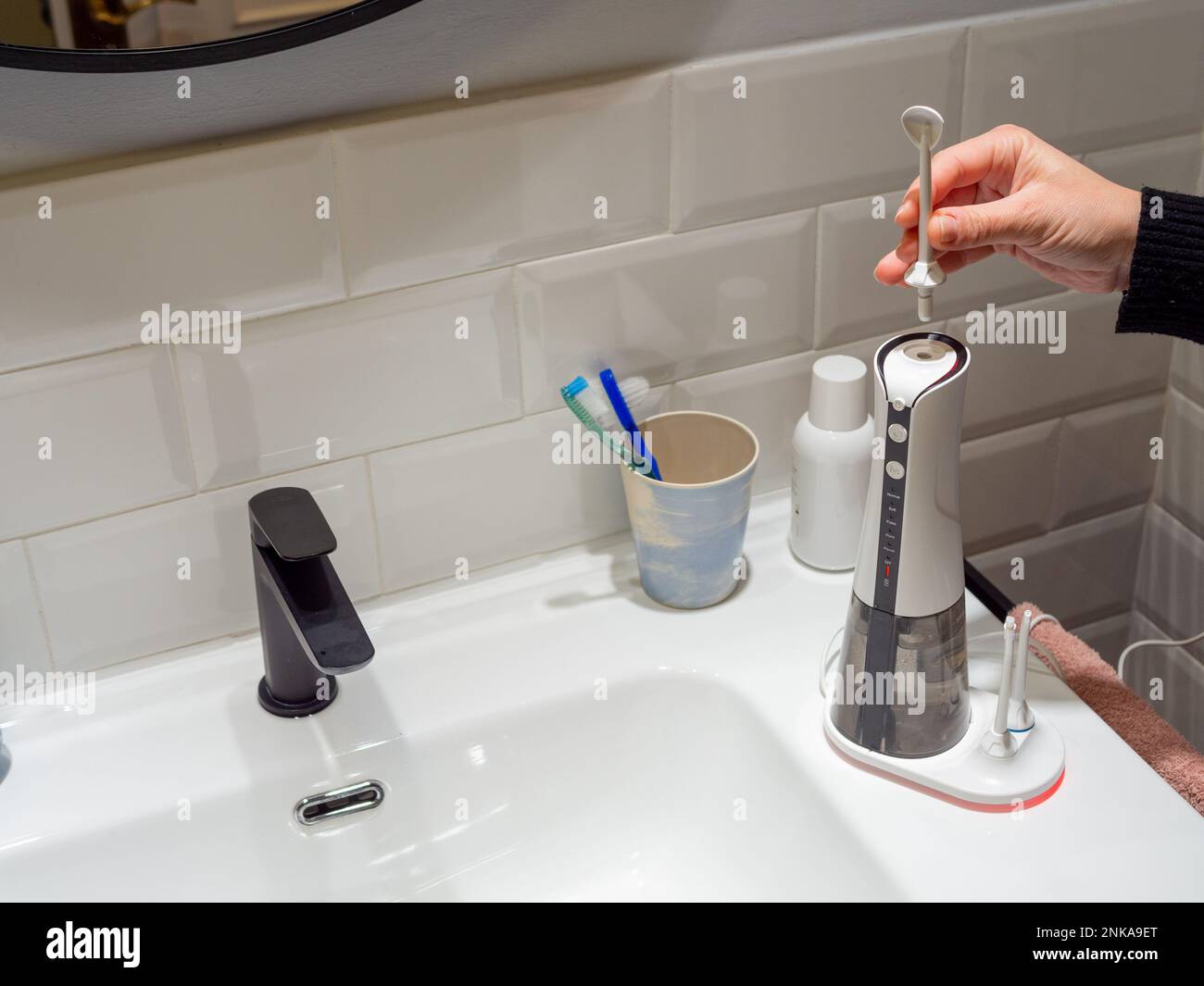 Le mani di giovane donna che cambiano la sua punta domestica del flosser dell'acqua dentale Foto Stock