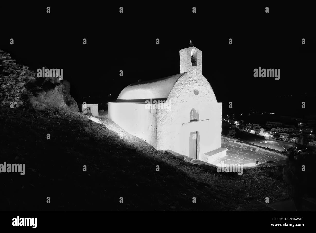 Vista di una piccola chiesa illuminata imbiancata a iOS Greece in cima alla collina Foto Stock