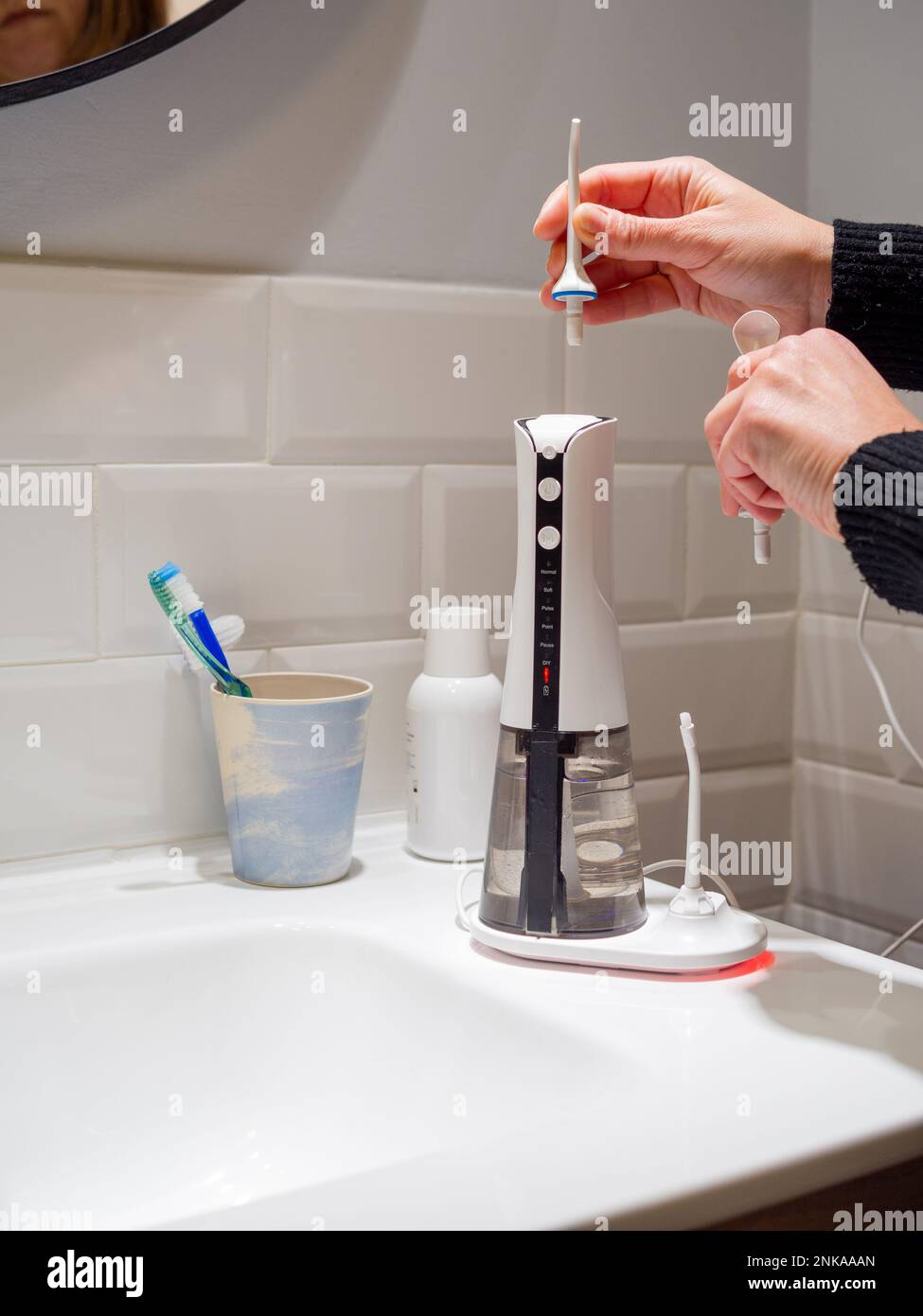 Le mani di giovane donna che cambiano la sua punta domestica del flosser dell'acqua dentale Foto Stock