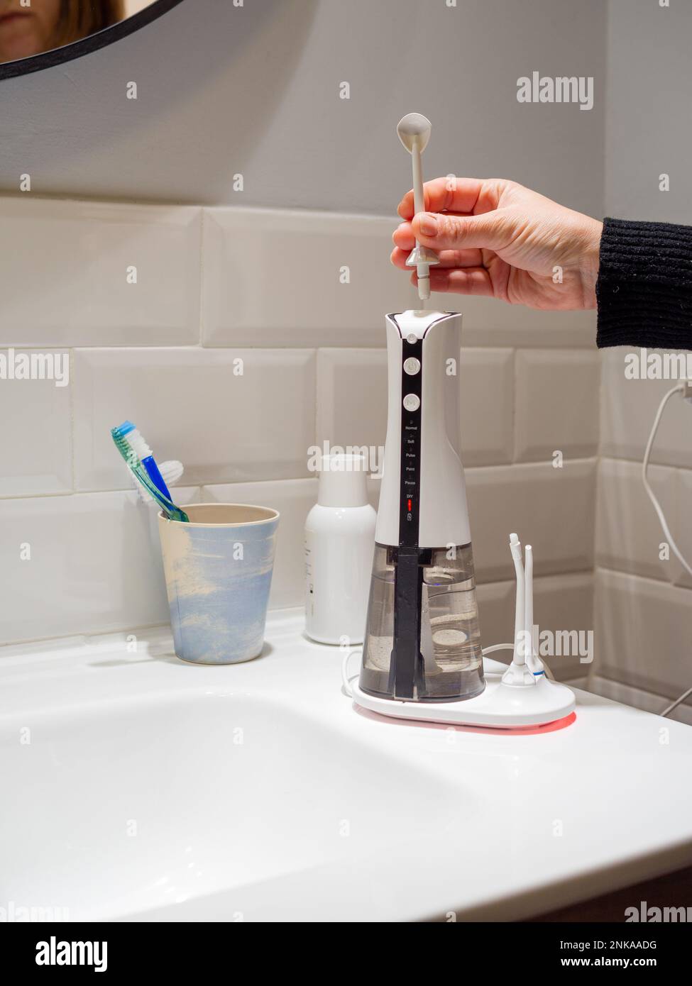 Le mani di giovane donna che cambiano la sua punta domestica del flosser dell'acqua dentale Foto Stock