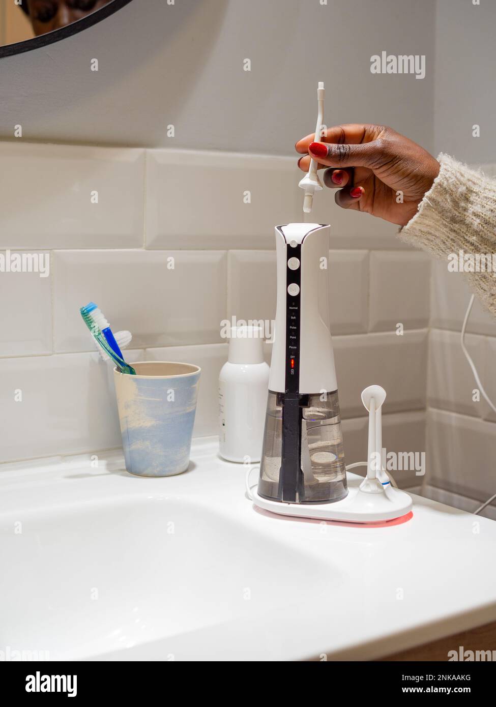Le mani di giovane donna che cambiano la sua punta domestica del flosser dell'acqua dentale Foto Stock