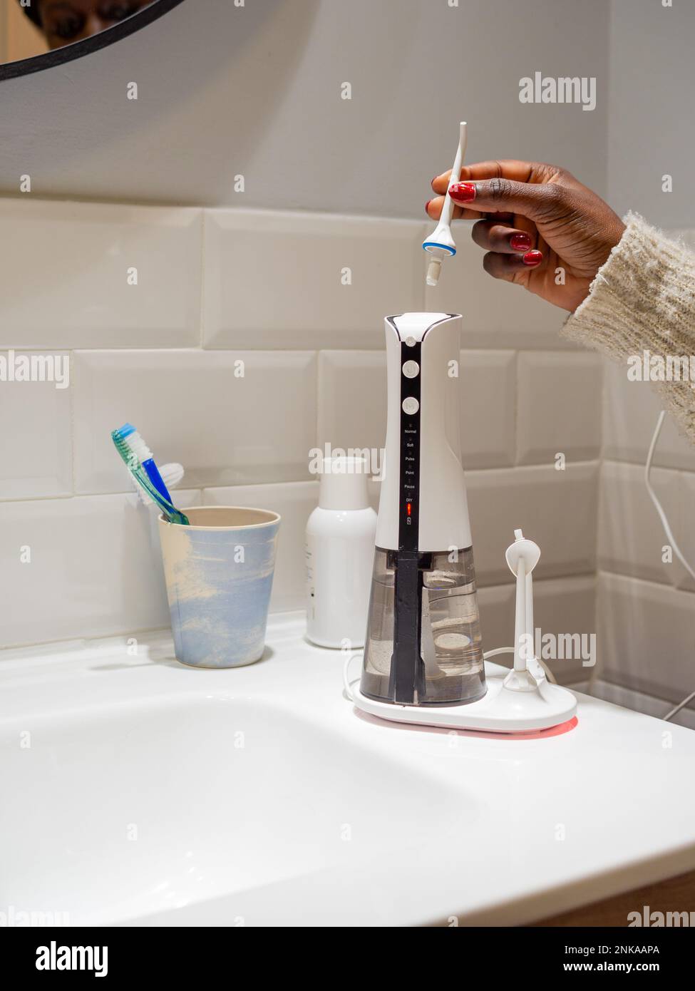 Le mani di giovane donna che cambiano la sua punta domestica del flosser dell'acqua dentale Foto Stock