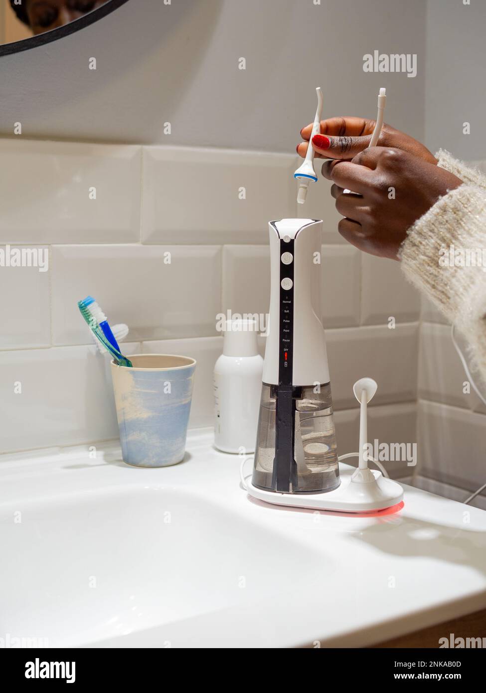 Le mani di giovane donna che cambiano la sua punta domestica del flosser dell'acqua dentale Foto Stock