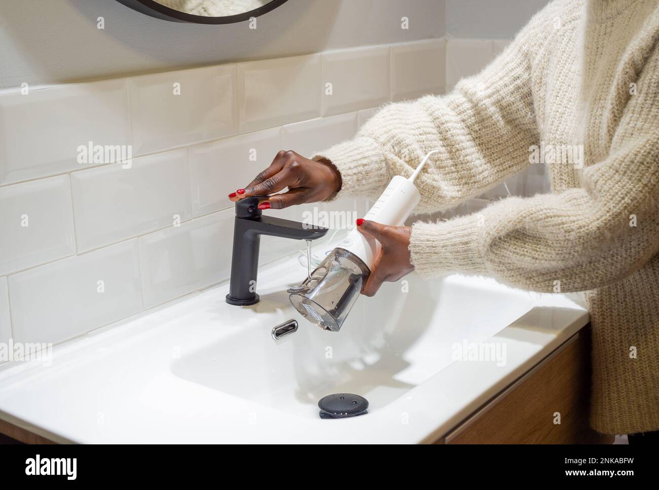 Senza sforzo Salute orale: Donna che riempie acqua serbatoio flosser al bagno bacino Foto Stock