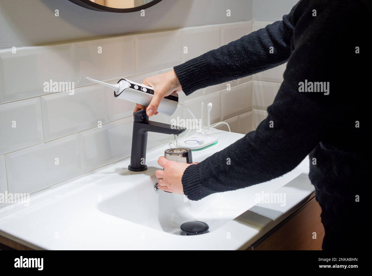 Senza sforzo Salute orale: Donna che riempie acqua serbatoio flosser al bagno bacino Foto Stock