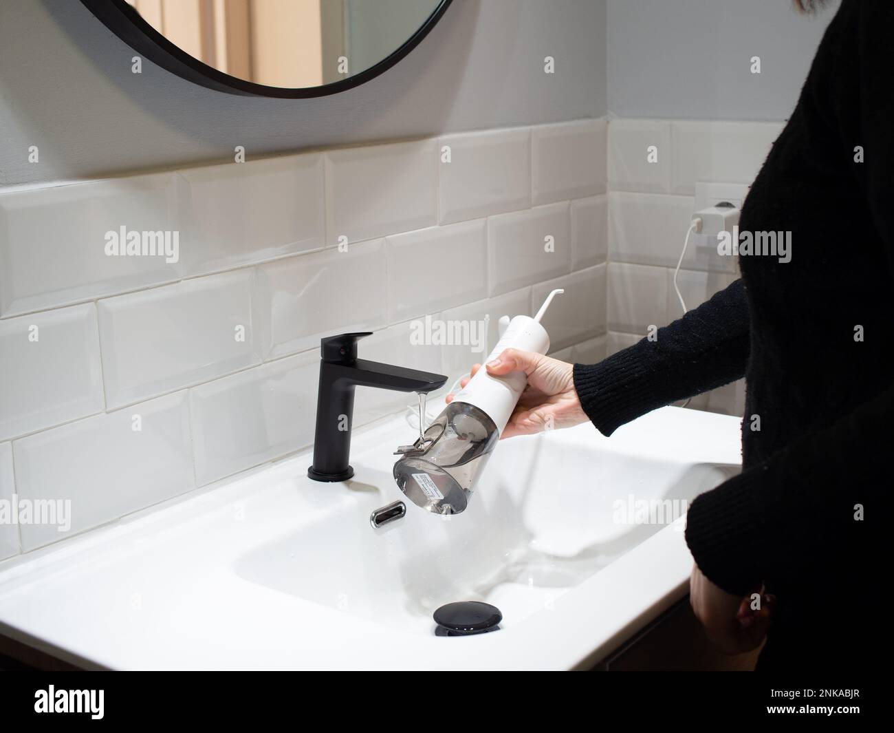 Senza sforzo Salute orale: Donna che riempie acqua serbatoio flosser al bagno bacino Foto Stock