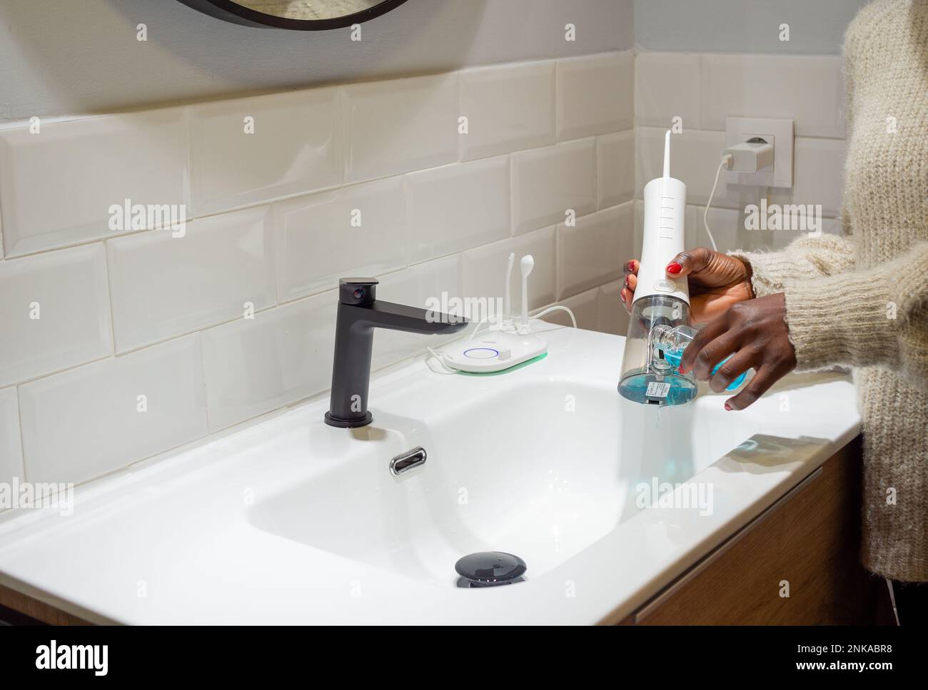 Senza sforzo Salute orale: Donna che riempie acqua serbatoio flosser con collutorio al bagno bacino Foto Stock