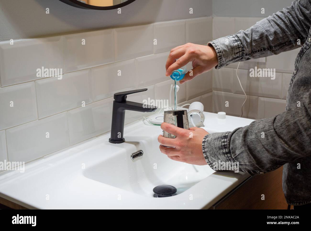 Senza sforzo Salute orale: Uomo riempimento acqua serbatoio flosser con collutorio al bagno bacino Foto Stock