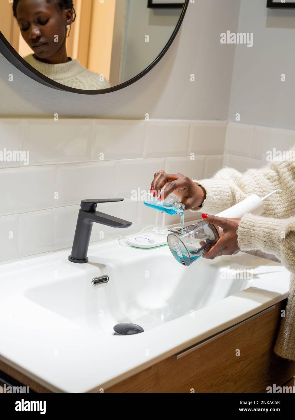 Senza sforzo Salute orale: Donna che riempie acqua serbatoio flosser con collutorio al bagno bacino Foto Stock
