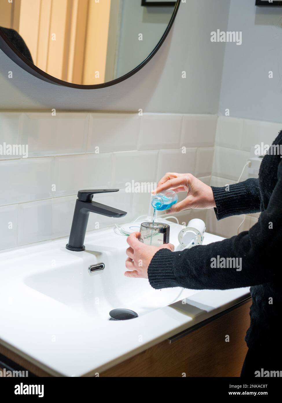 Senza sforzo Salute orale: Donna che riempie acqua serbatoio flosser con collutorio al bagno bacino Foto Stock