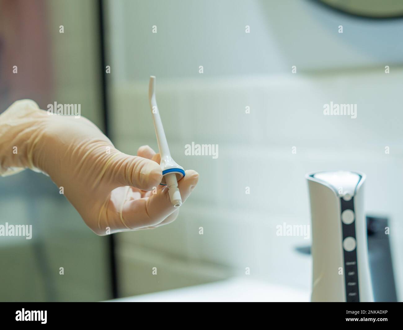 Mano del dentista che mostra come usare il flosser domestico dell'acqua dentale per una pulizia profonda nel paese Foto Stock