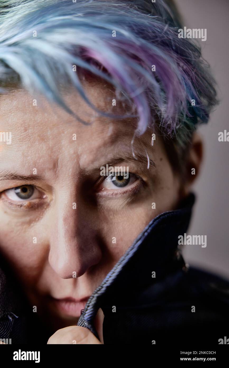 Donna androgina con i capelli tinti tira il colletto della sua giacca in denim, ritratto Foto Stock