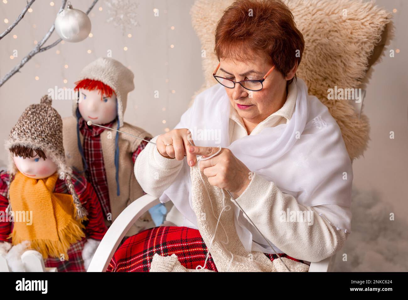 Una bella donna anziana scaglia a maglia le sue nipoti in un accordo di Natale. In studio Foto Stock