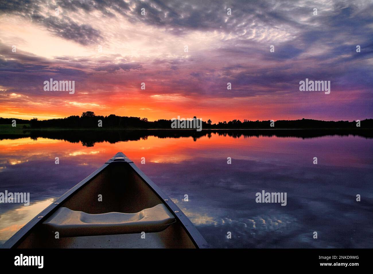 Una canoa indica il tramonto su un tranquillo lago Minnesota. Foto Stock