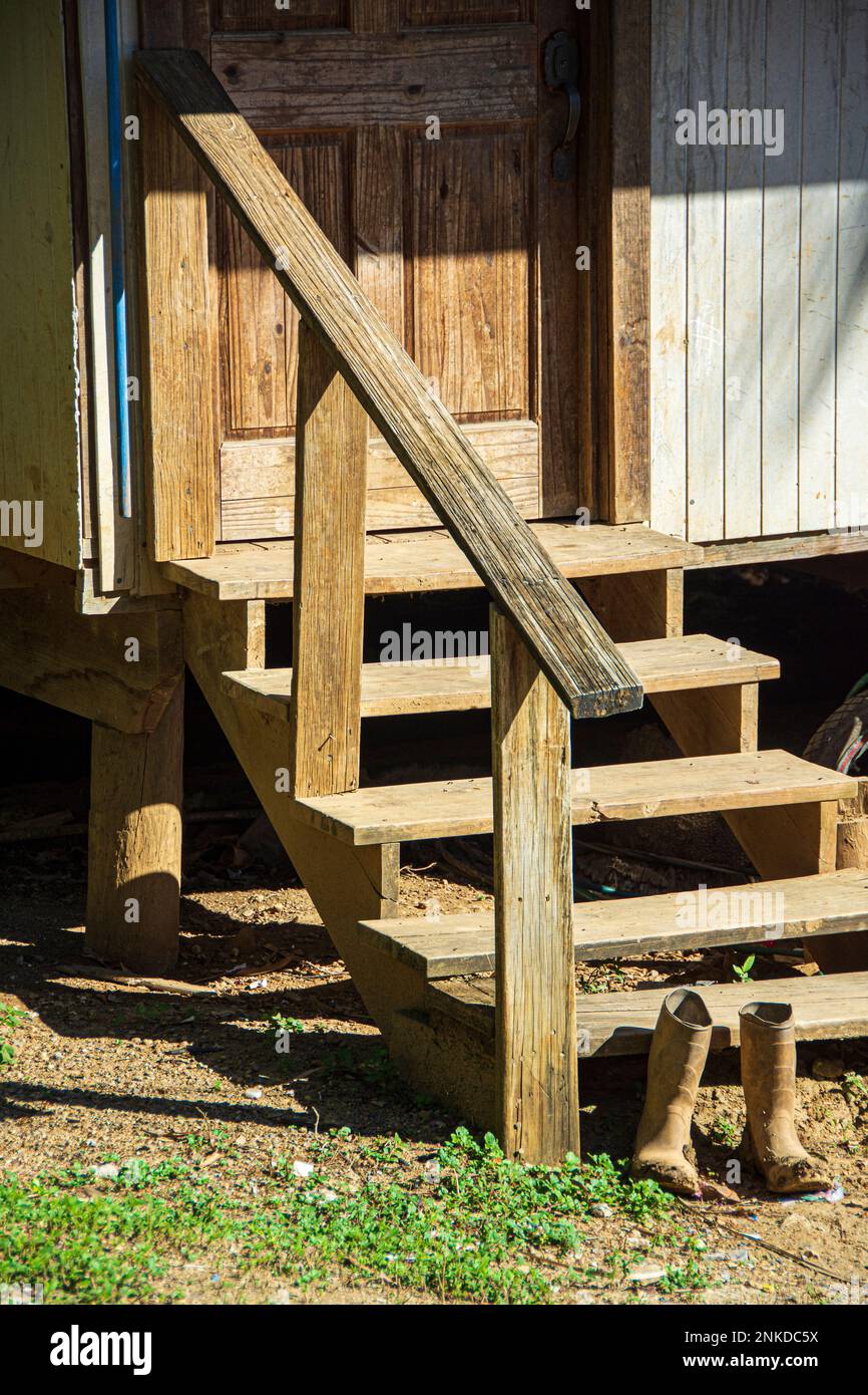 Un vecchio, sporco paio di stivali da lavoro da gradini di legno che porta ad una porta. Roatan, Honduras. Foto Stock
