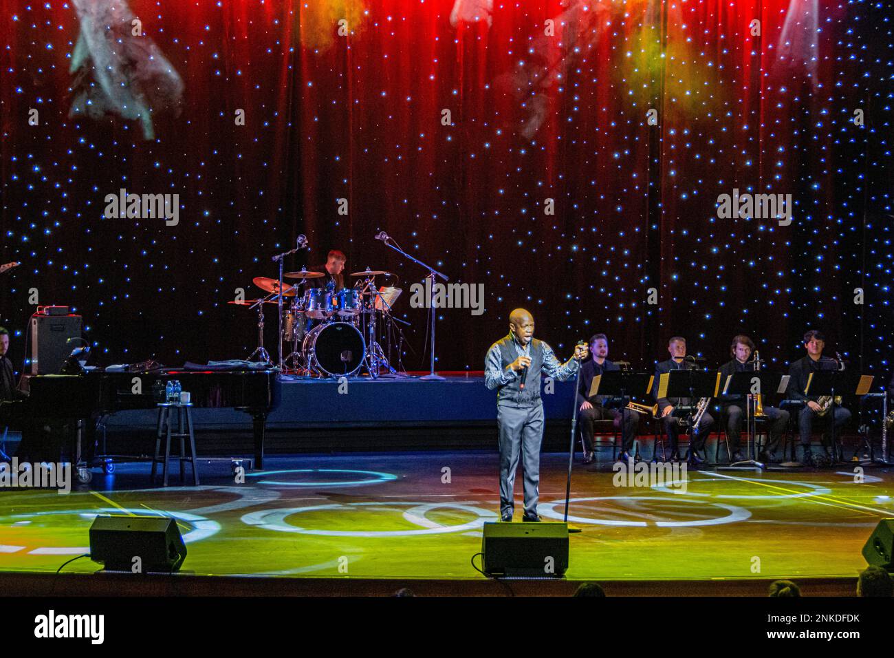 Un esecutore con la sua band dietro di lui. Parte di uno spettacolo sull'Allure of the Seas, Royal Caribbean Cruise Lines. Foto Stock