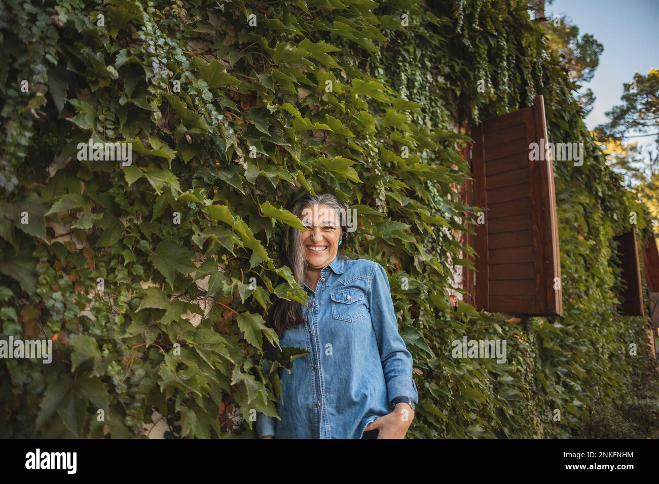 Donna matura felice in piedi sulla facciata troppo grande Foto Stock