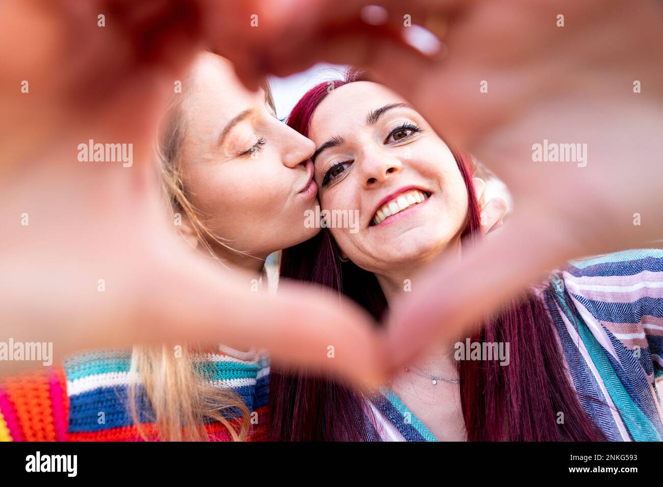 Donna che bacia amico visto attraverso la forma del cuore Foto Stock