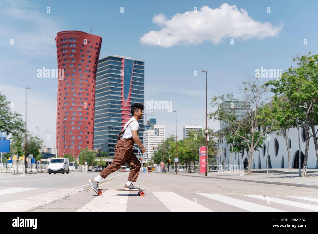 Giovane uomo skateboard sulla zebra traversata in città Foto Stock