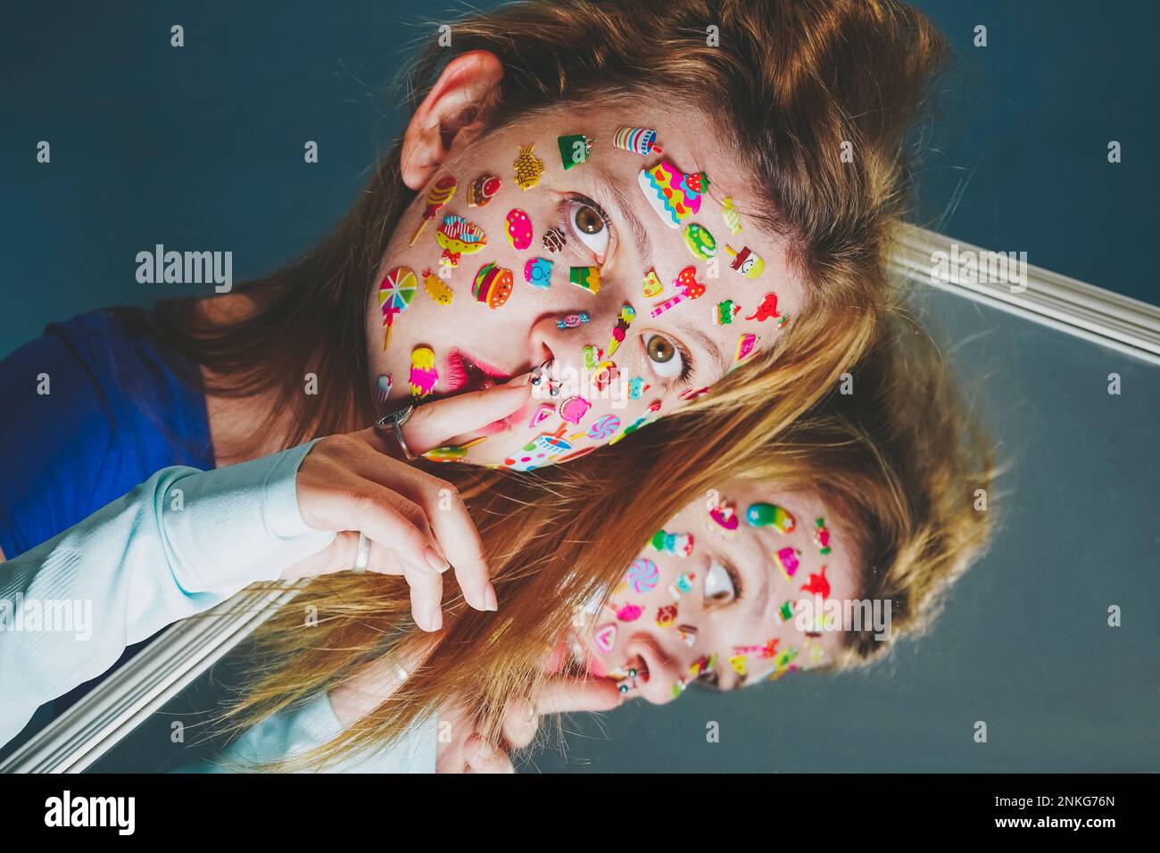 Donna con adesivi sul viso e dito sulle labbra su sfondo blu Foto Stock