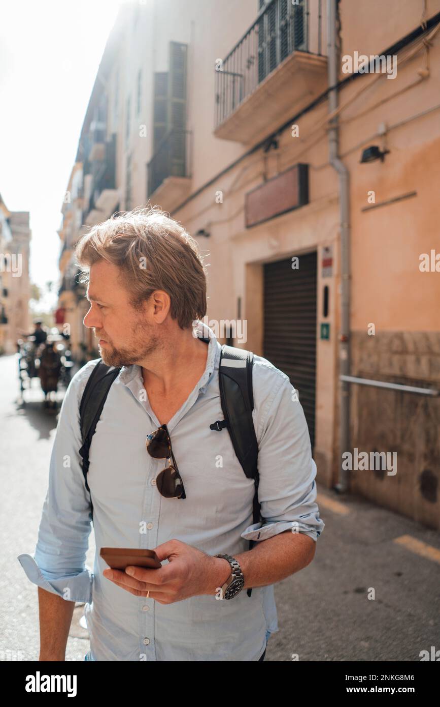 Uomo maturo con smartphone che cammina per strada Foto Stock