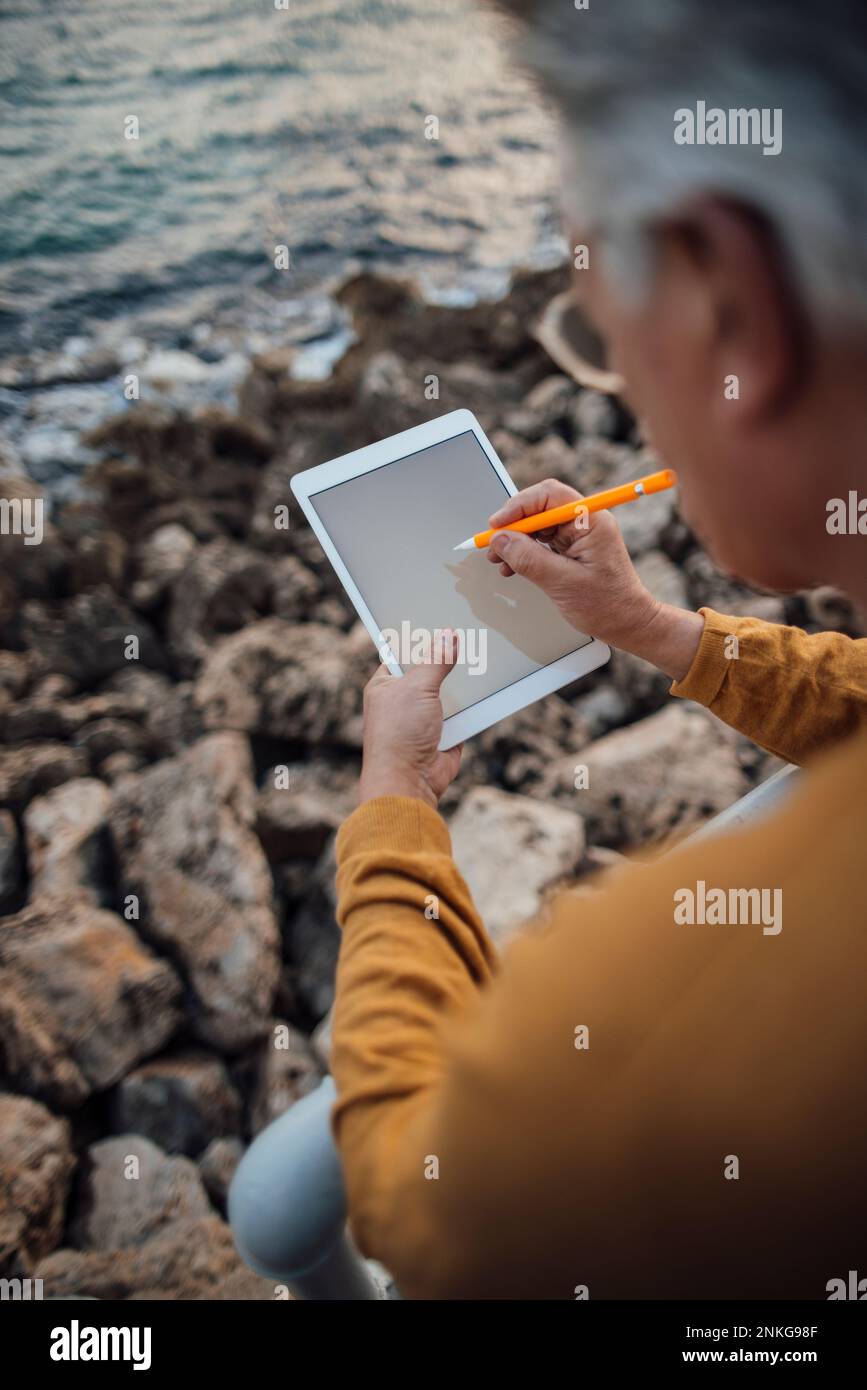 Uomo anziano che utilizza un PC tablet con penna digitalizzata Foto Stock