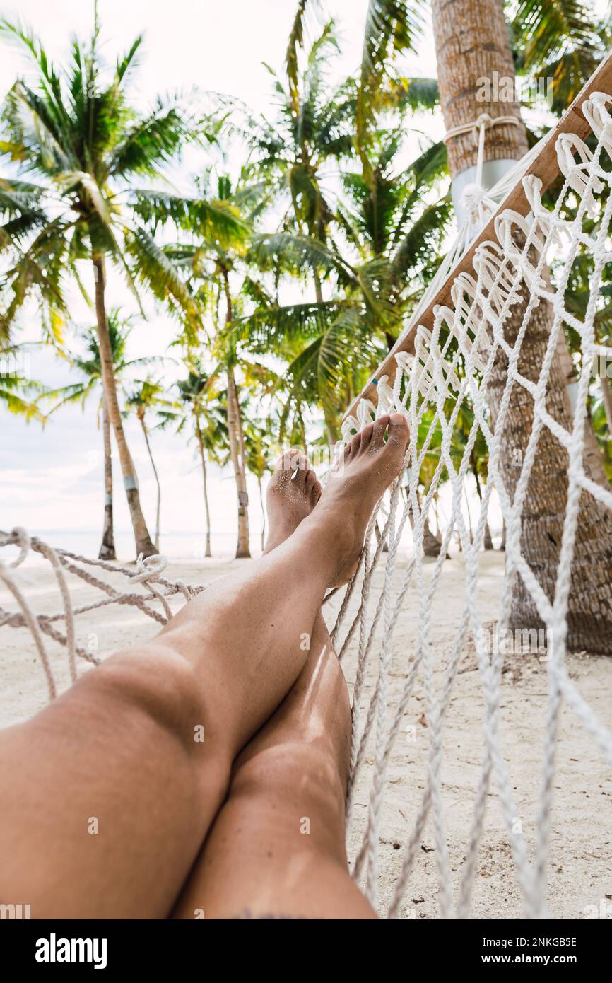 Uomo seduto in amaca sulla spiaggia, Bohol, Filippine Foto Stock