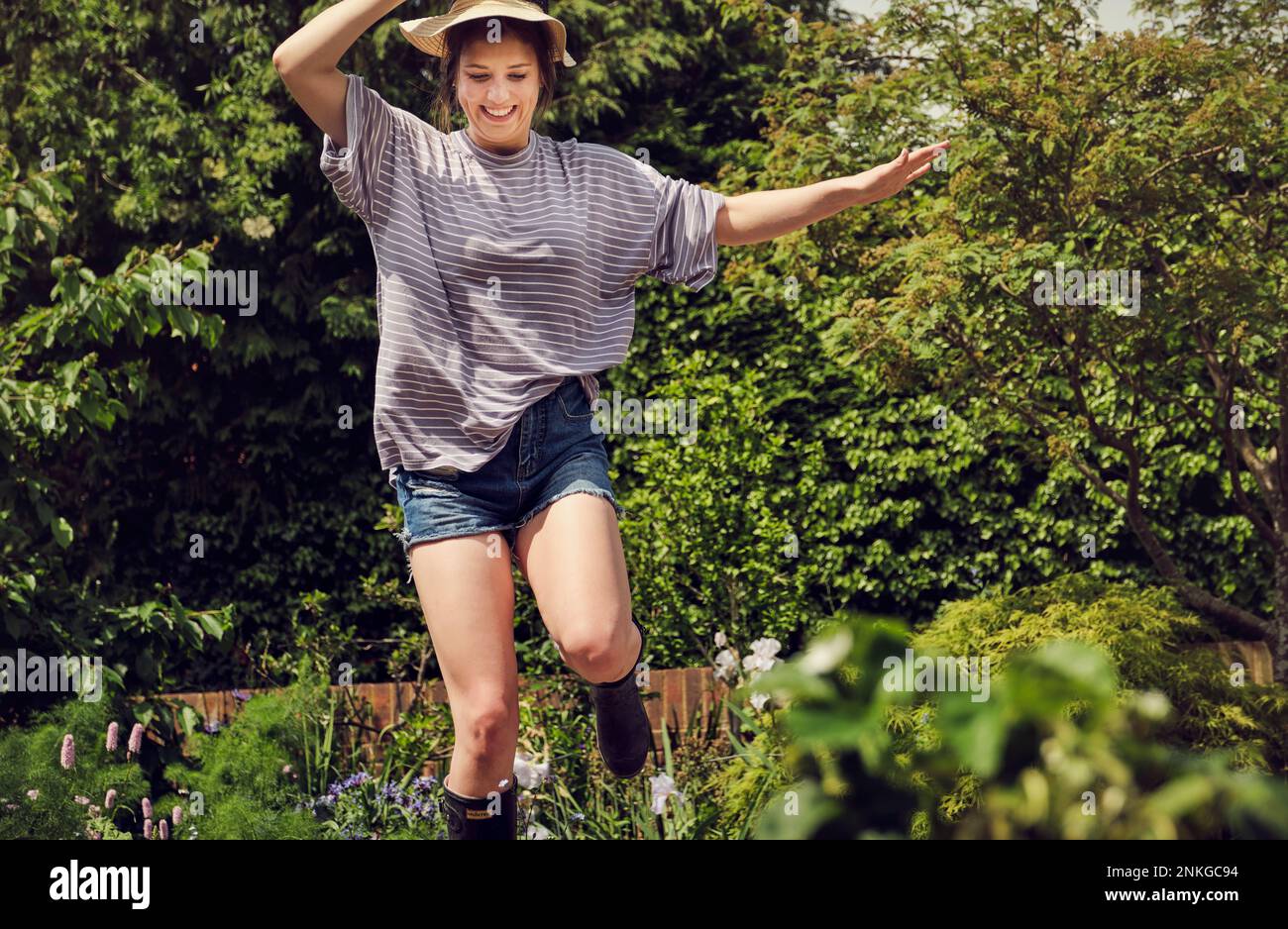 Giovane donna eccitata che salta nel cortile posteriore Foto Stock