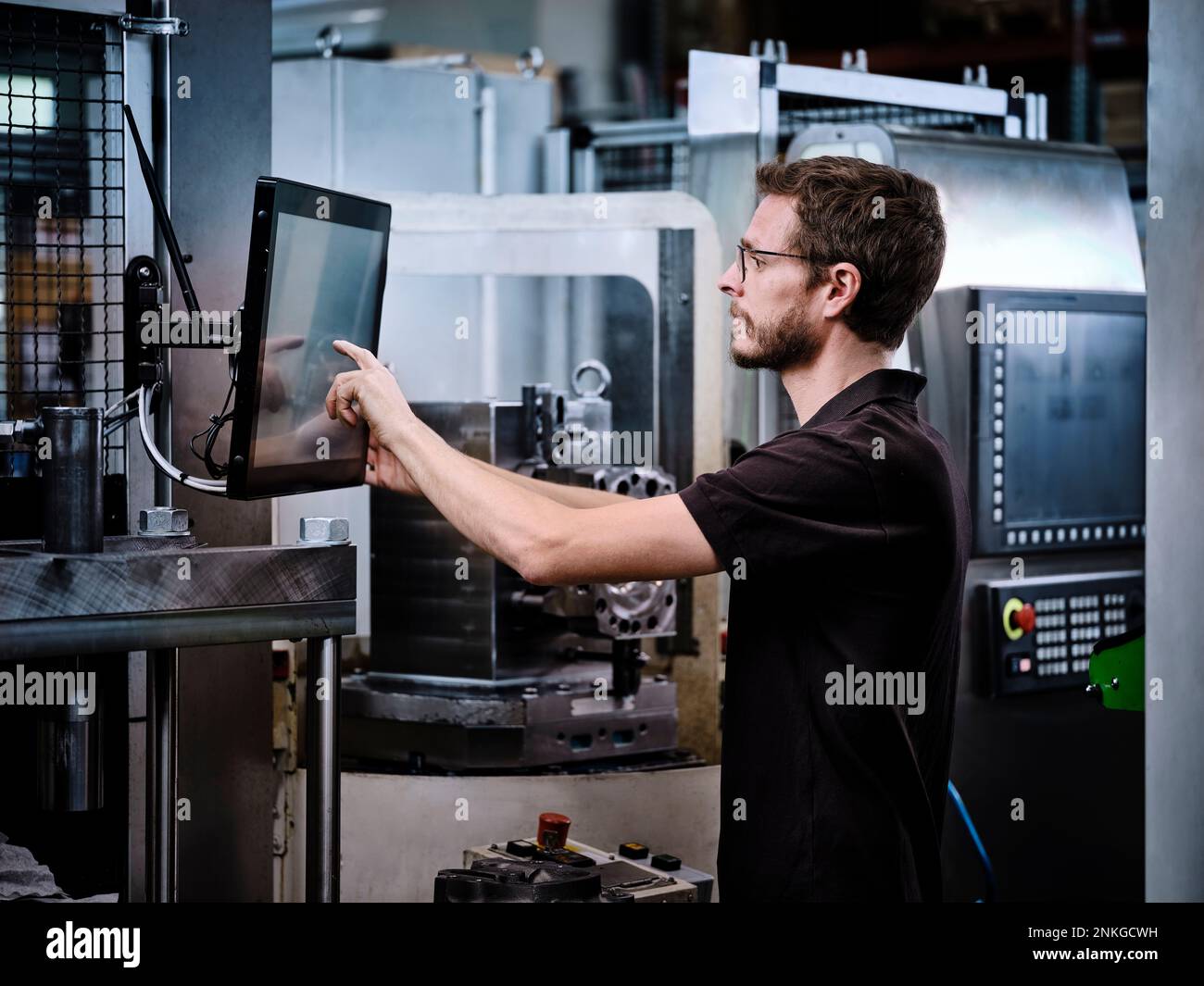 Tecnico che utilizza la macchina in fabbrica moderna Foto Stock
