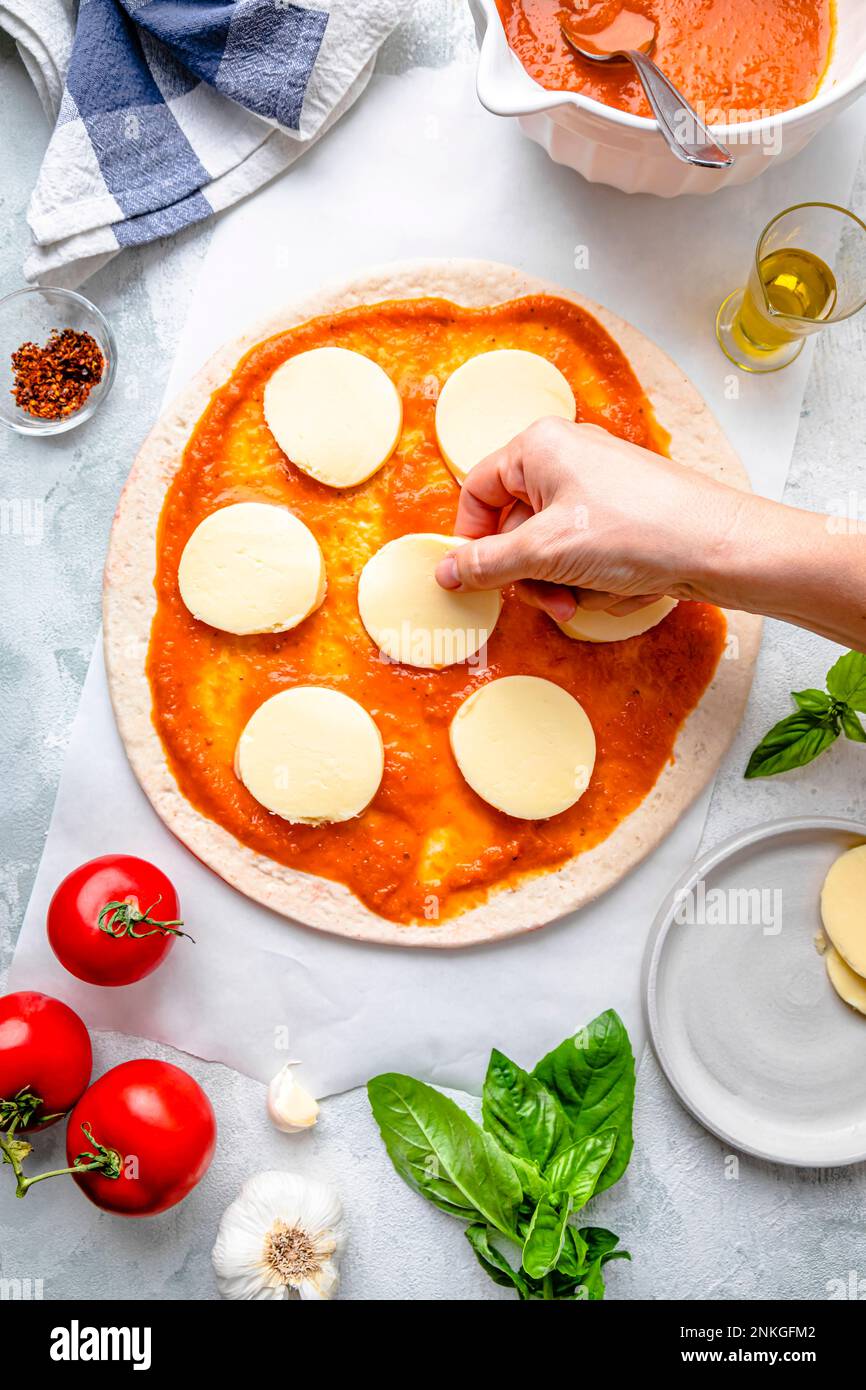 Mano di donna che prepara la pizza sul tavolo Foto Stock