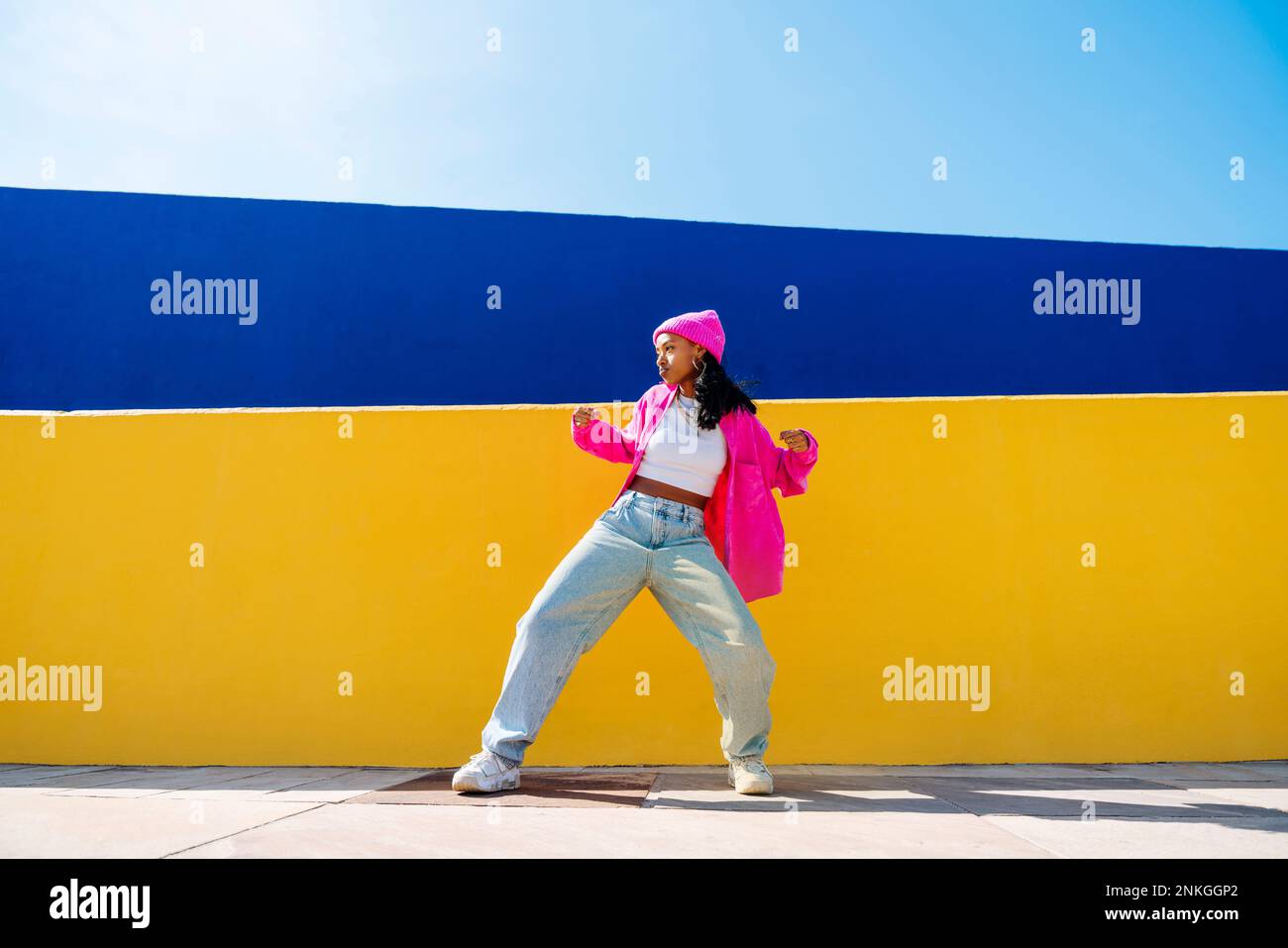 Giovane donna che balla di fronte alla parete a due colori Foto Stock