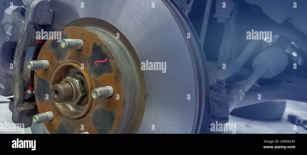 Impianto frenante a disco per auto. Sospensione della vettura in corso di sostituzione di nuovi pneumatici in officina. Controllo meccanico del freno a disco per auto e riparazione. Rottura del disco Foto Stock