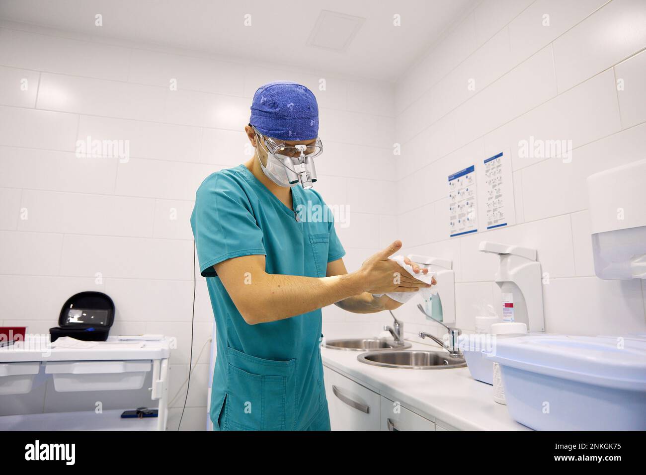 Medico strofinare le mani con carta tissue in ospedale Foto Stock