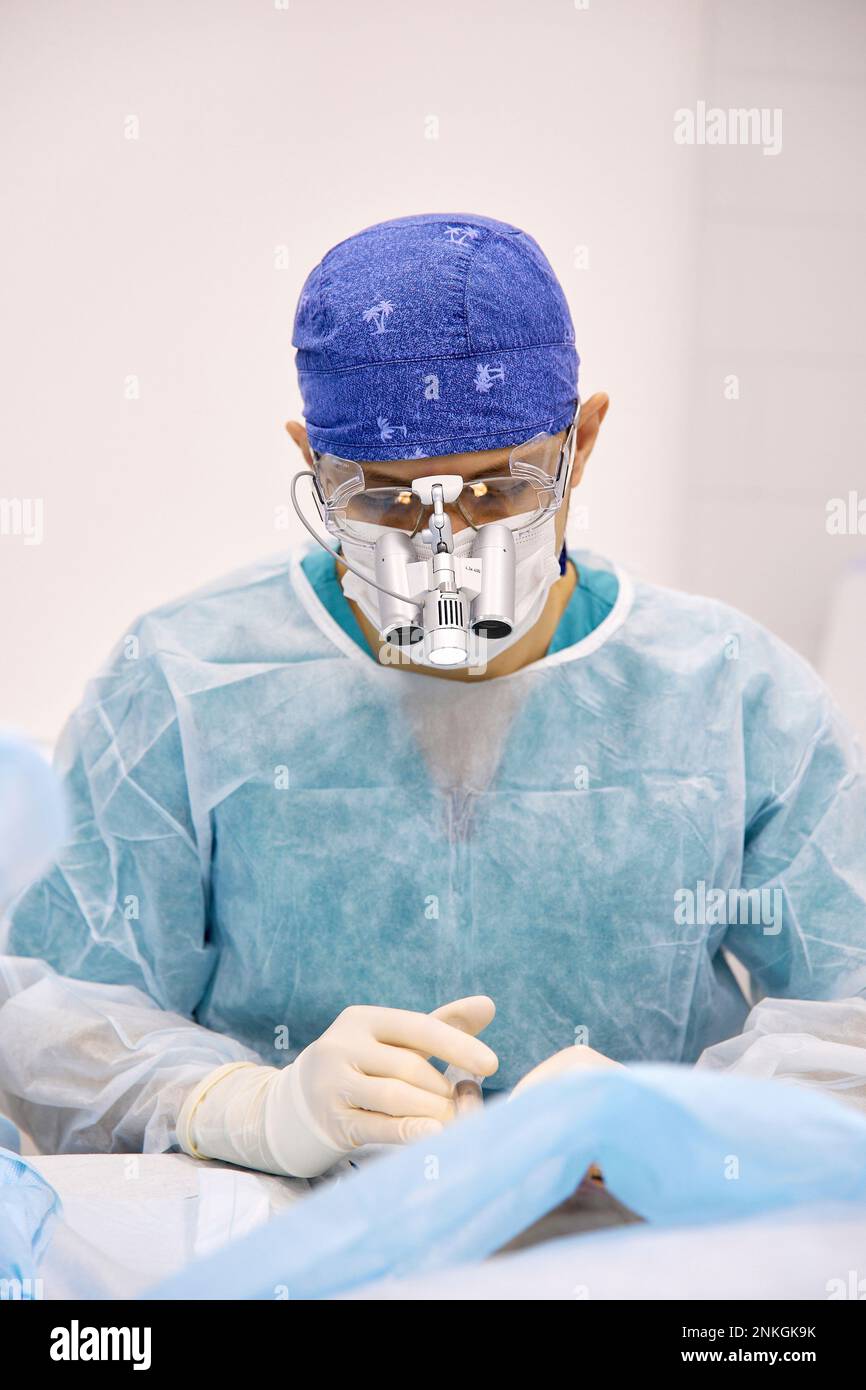 Il medico che esegue un intervento chirurgico agli occhi del paziente in sala operatoria Foto Stock