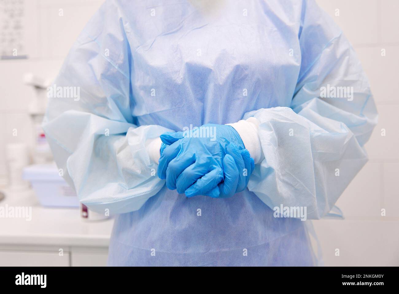 Medico maturo che indossa guanti protettivi e abito operatorio in piedi in clinica Foto Stock