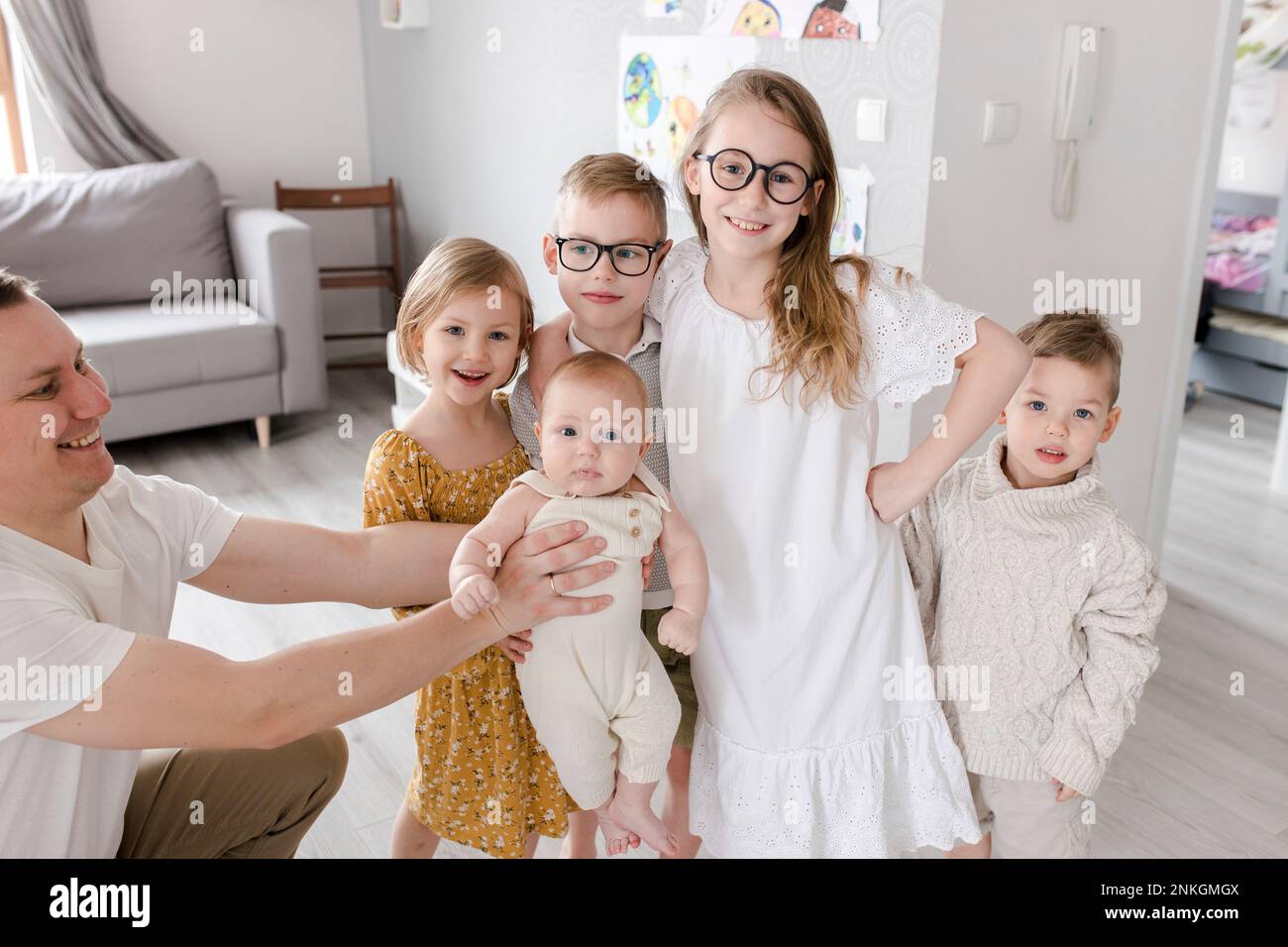 Padre e figli in piedi insieme nel soggiorno di casa Foto Stock