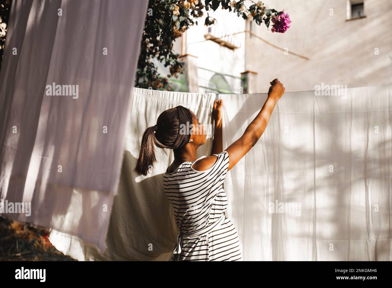Donna incinta che appende lavanderia nel cortile Foto Stock