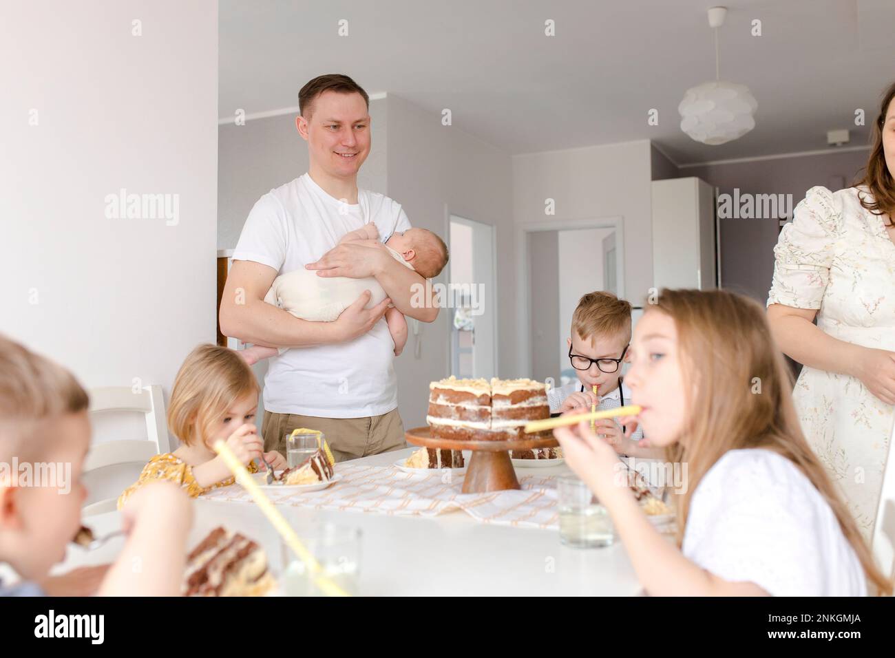Padre che porta figlio con i bambini che mangiano la torta seduto al tavolo Foto Stock