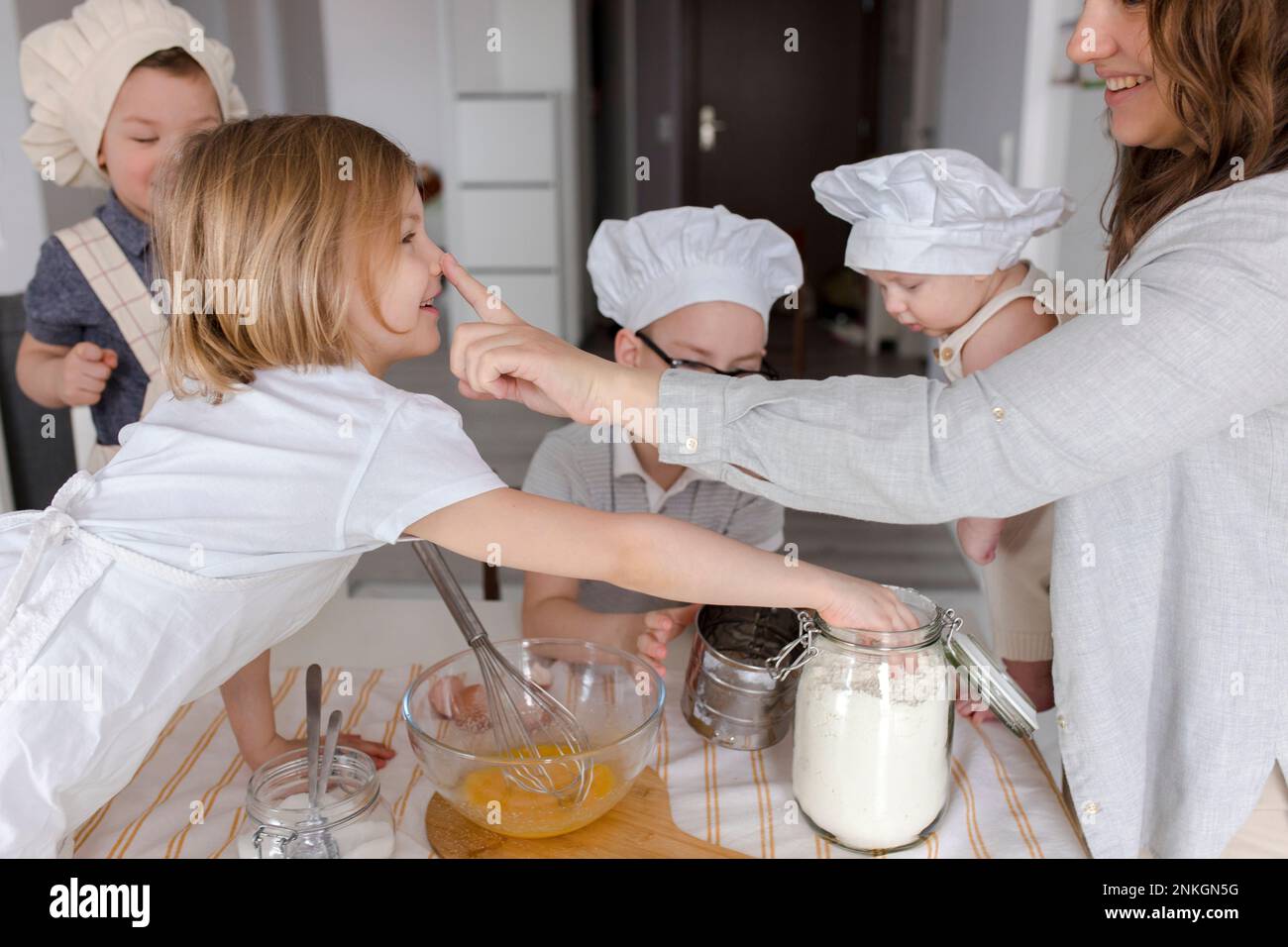 Madre che tocca il naso della ragazza con i bambini che si divertono sullo sfondo Foto Stock