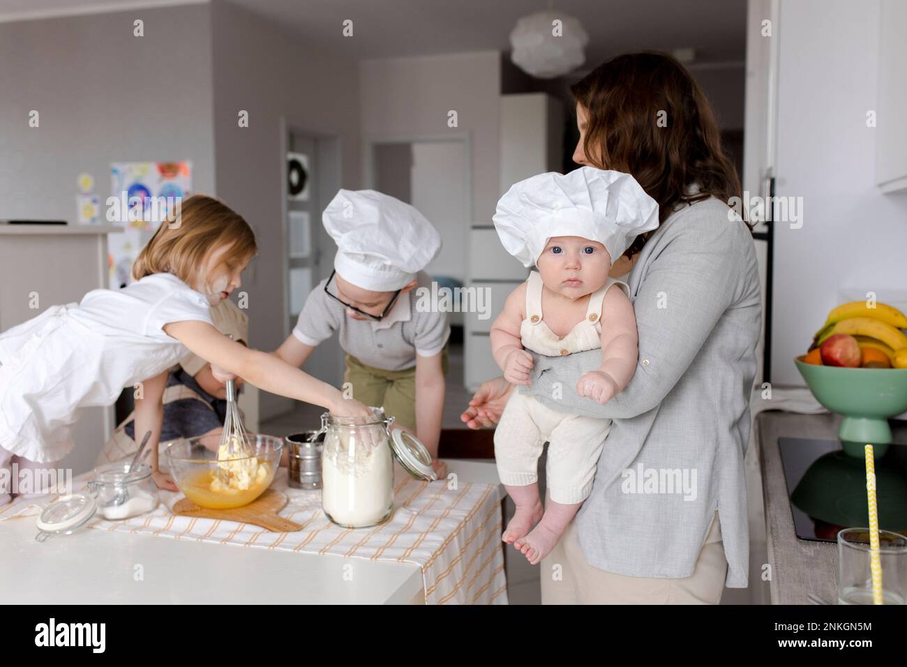 Madre che porta il ragazzo con i bambini che preparano l'impasto in cucina Foto Stock