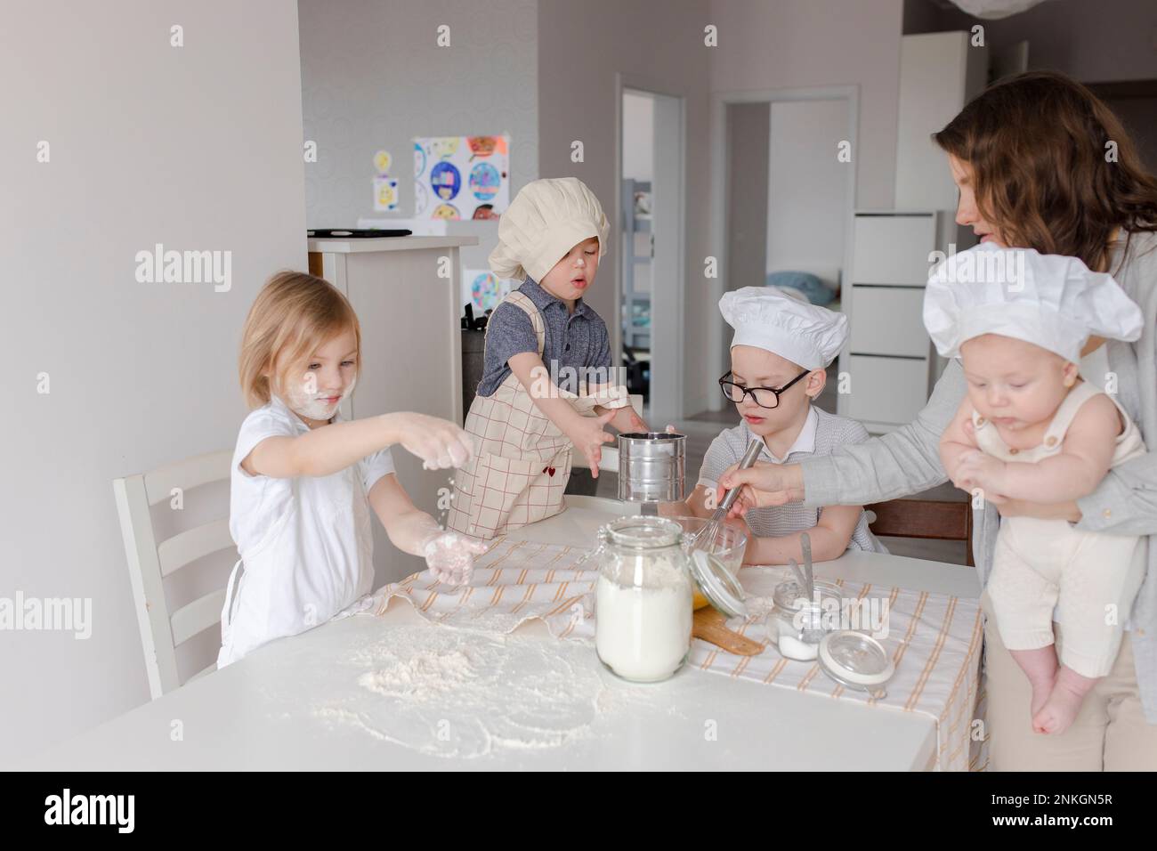 Madre con bambini che si divertono a preparare l'impasto in cucina Foto Stock
