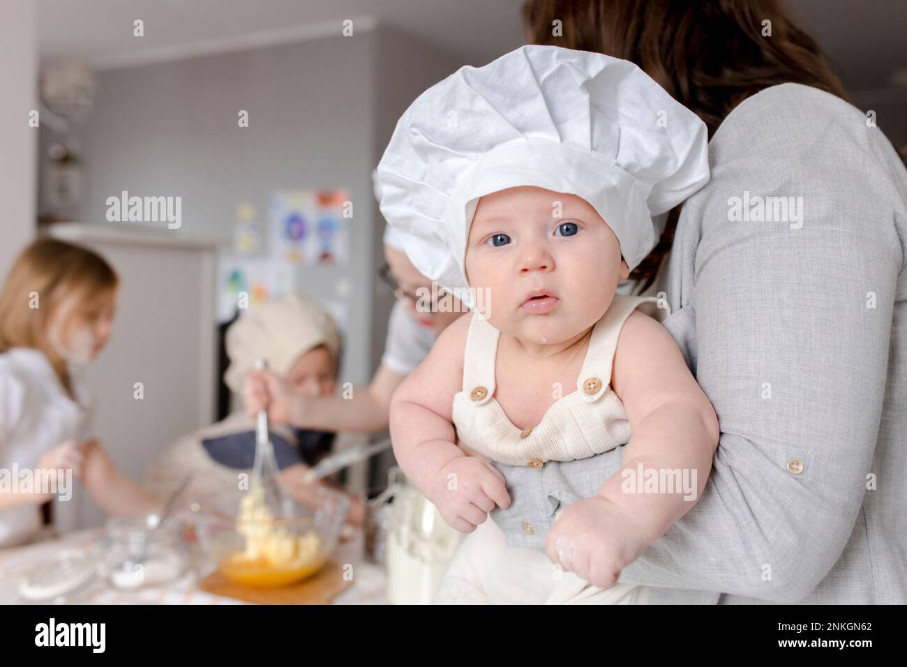 Madre che tiene un ragazzo carino con il cappello dello chef a casa Foto Stock